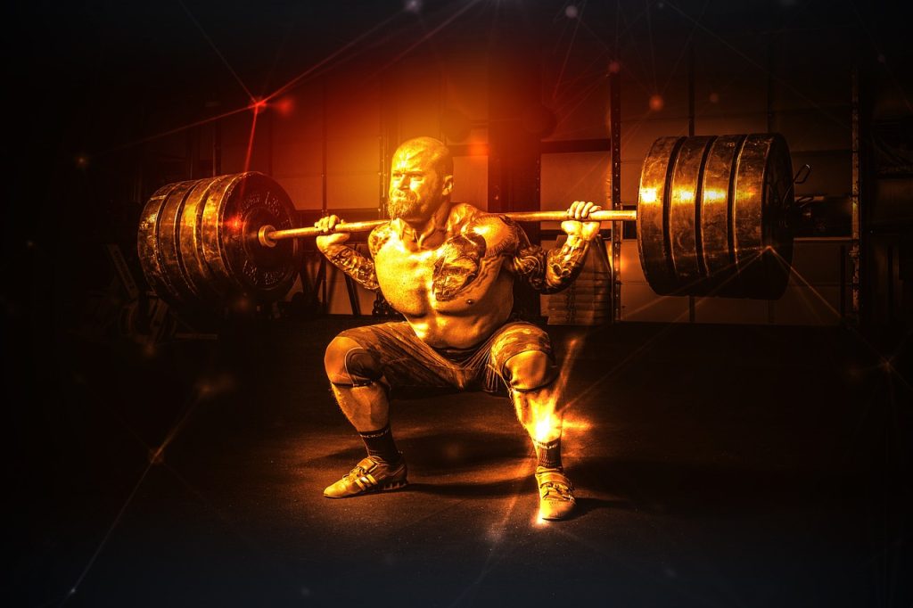 An image of a muscular man squatting with 8 plates on his barbell in a darkly lit room